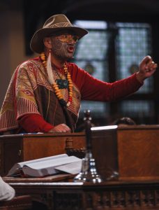 New Zealand politician Rawiri Waititi speaking in the debating chamber at the cambridge union society, wearing traditional Maori clothing
