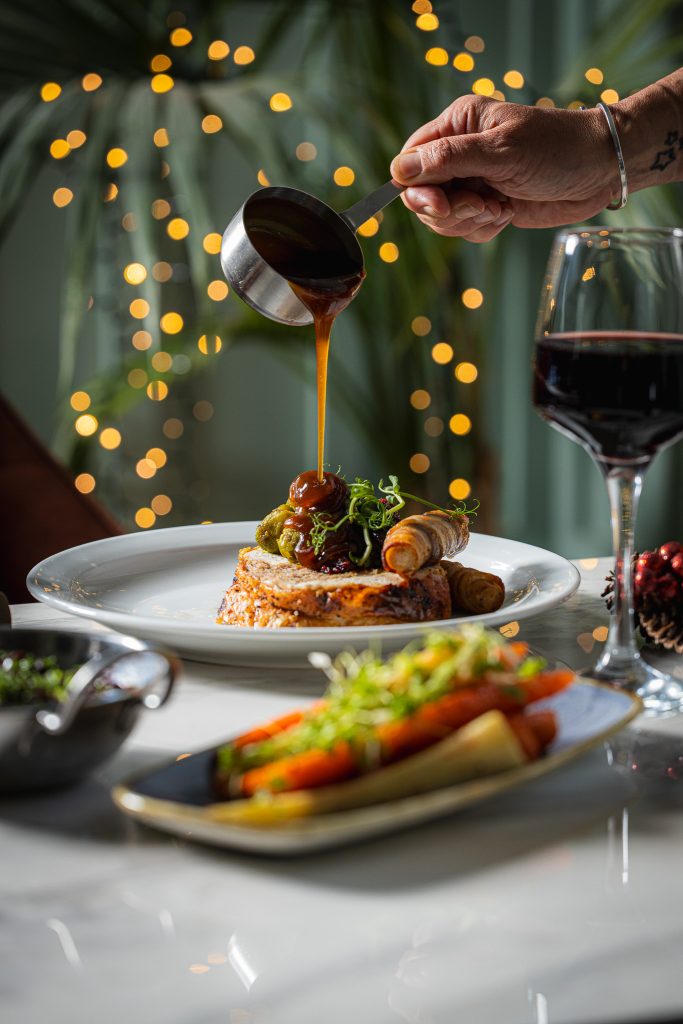 Christmas turkey dinner with gravy being poured and a glass of red wine at the orator